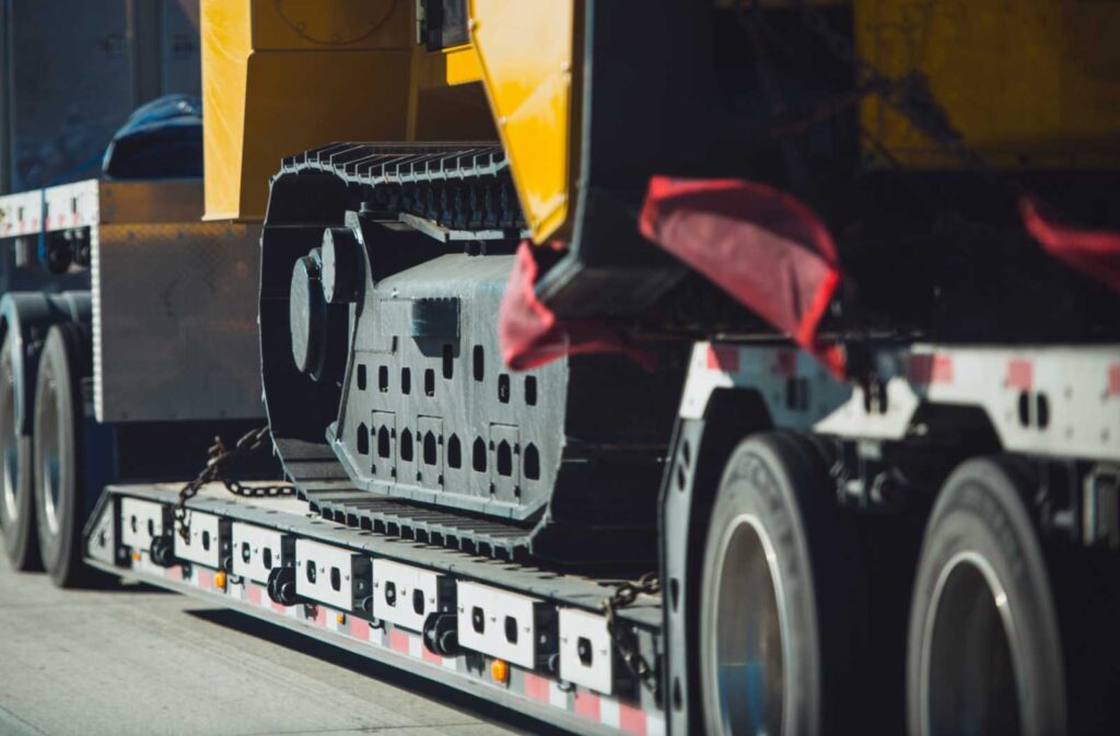 Heavy construction machinery secured on a flatbed trailer for transportation